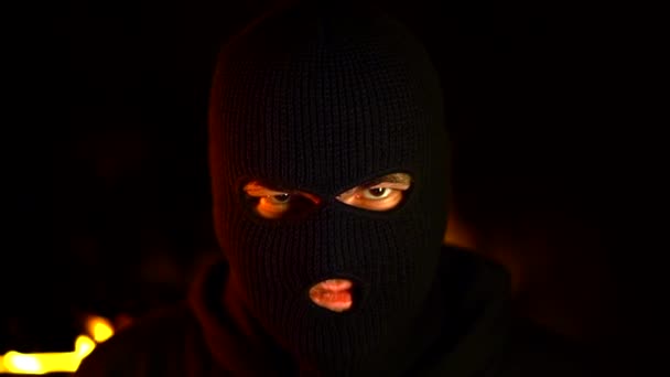 Портрет протестующего активиста в черной балаклаве против горящих баррикад ночью. Концепция забастовок, политических конфликтов и конфронтации — стоковое видео