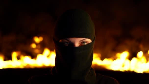 Retrato de ativista protestante feminino em balaclava preta contra barricadas em chamas à noite. Conceito de greves, conflitos políticos e confronto . — Vídeo de Stock