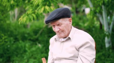 Çok eski beyaz adam portresi. Büyükbabam üzgün. Portre: yaşlı, yaşlı, yalnızlık, yüzünde kırışıklıklar çok kıdemli. Dışarıda tek başına oturan dalgın yaşlı bir adamın yakın çekimi. 