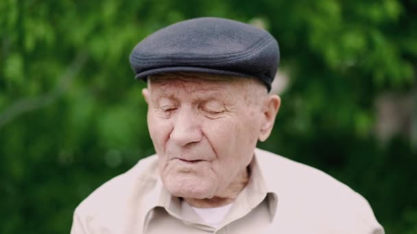 Очень старый кавказский мужской портрет. Дедушка грустит. Портрет: пожилые люди, одиночество, пожилые люди с морщинами на лице. Крупный план задумчивого старика, сидящего один на улице . — стоковое видео
