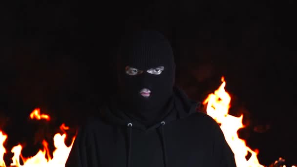 Portrait de jeune homme en cagoule noire sur fond de feu de nuit flamboyant — Video