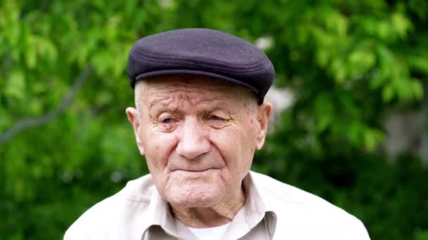 Retrato de hombre caucásico muy viejo. Abuelo con sombrero. Retrato: anciano, anciano, soledad, mayor con muchas arrugas en la cara. Primer plano de un anciano pensativo sentado solo al aire libre . — Vídeo de stock