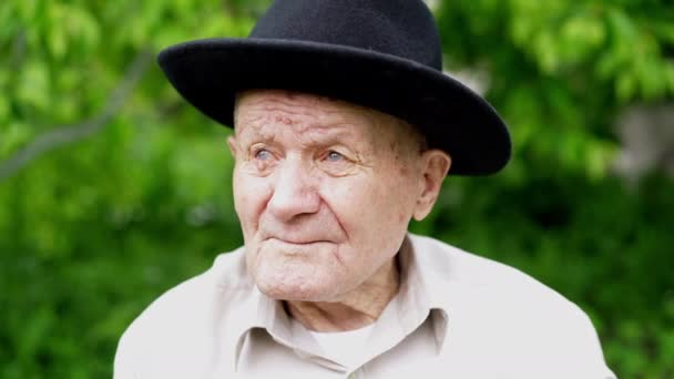 Retrato de homem caucasiano muito antigo. Avô de chapéu. Retrato: idoso, idoso, solidão, idoso com muitas rugas no rosto. Close-up de um velho pensativo sentado sozinho ao ar livre . — Vídeo de Stock