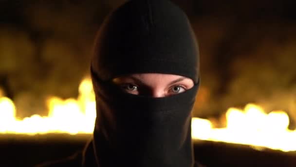 Retrato de ativista protestante feminino em balaclava preta contra barricadas em chamas à noite. Conceito de greves, conflitos políticos e confronto — Vídeo de Stock