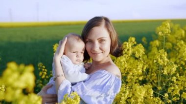 Sarı alanda eğlenceli yenidoğan oğlu ile Genç Anne portresi. Aşk, Aile, sevinç konsepti.