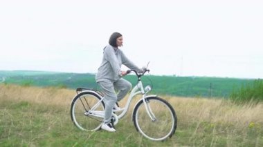 Beyaz geçmişe dönük bisiklet süren bir kadın. 