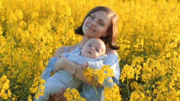 Портрет молодой матери с новорожденным ребенком, веселящимся на желтом поле. Понятие любви, семьи, радости — стоковое видео