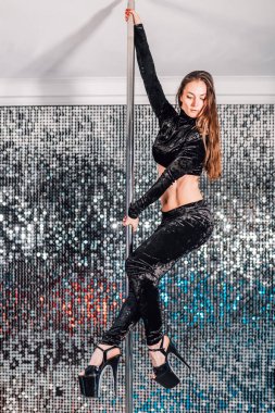 Kadın Pylon ile numara yapıyor. Siyah dans genç striptizci stüdyo veya kulüp Pole ile cinsel. Parlayan duvar arka planda poledance