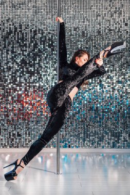 Kadın Pylon ile numara yapıyor. Siyah dans genç striptizci stüdyo veya kulüp Pole ile cinsel. Parlayan duvar arka planda poledance