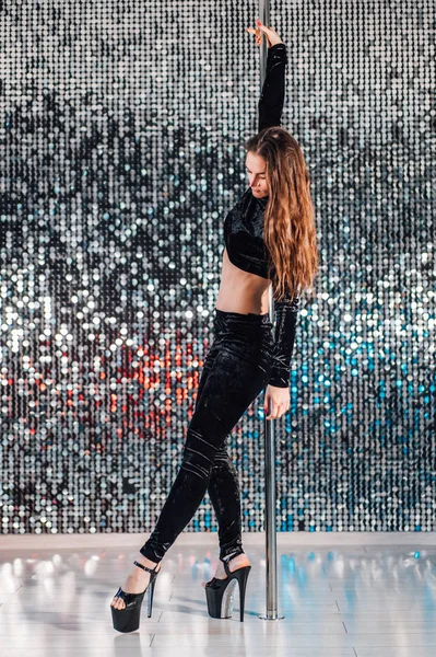 Kadın hileler yapıyor, stüdyoda Pylon ile alıştırma yapıyor. Siyah danslı genç striptizci kulüpte Pole ile cinsel. Parlayan duvar arka planda poledance