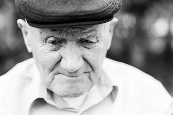 Retrato de anciano. Abuelo con sombrero. Retrato: anciano, anciano, soledad, mayor con muchas arrugas en la cara. Primer plano de un hombre pensativo sentado solo. Blanco y negro — Foto de Stock