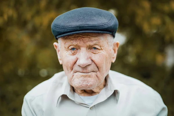 Retrato de hombre caucásico muy viejo. Abuelo con sombrero. Retrato: anciano, anciano, soledad, mayor con muchas arrugas en la cara. Primer plano de un anciano pensativo sentado solo al aire libre . — Foto de Stock