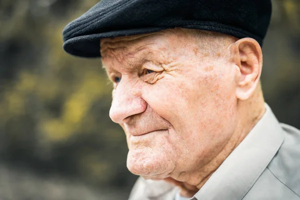 Retrato de hombre caucásico muy viejo. Abuelo con sombrero. Retrato: anciano, anciano, soledad, mayor con muchas arrugas en la cara. Primer plano de un anciano pensativo sentado solo al aire libre . — Foto de Stock