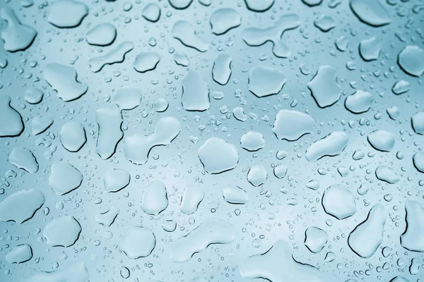 Vista de perto de gotas de água caindo em vidro. Chuva correndo na janela. Temporada chuvosa, outono. Gotas de chuva caem, céu cinzento . — Fotografia de Stock