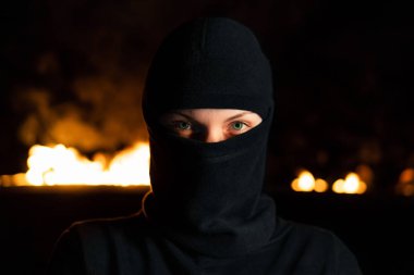 Geceleri yanan barikatlara karşı siyah balaclava kadın protestocu aktivist portresi. Grevkavramı, siyasi çatışmalar ve çatışma