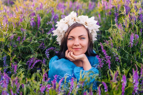 Ung vacker kvinna med blomkrans sitter i lila fält. Porträtt av flicka i blå kläder. — Stockfoto