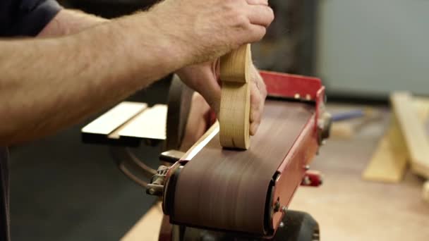 Hands of carpenter sharpens wooden part on grinding machine in factory atelier. Handwork concept, woodworking workshop. — Stock Video