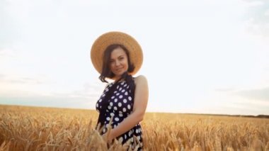 Neşeli, neşeli, mutlu bir kadın. Retro giyinmiş kız hasır şapka ve siyah elbise gün batımı nda buğday alanında etrafında dönen. 
