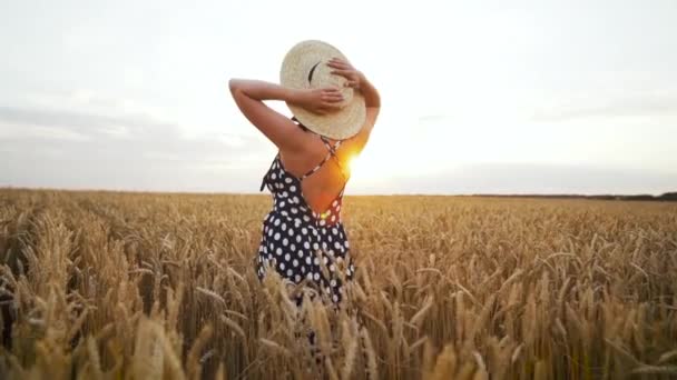 Ragazza irriconoscibile con cappello di paglia che cammina nel campo di grano dorato. Elegante signora sexy in abito lungo vintage. Ora d'oro. Raccolta, concetto di viaggio . — Video Stock