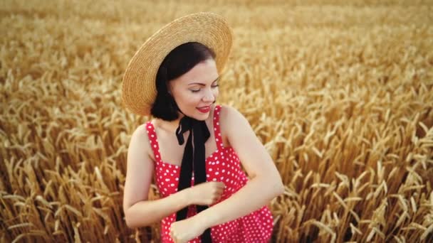 Bella donna in abito rosso e cappello di paglia divertente danza nel campo di grano dorato. Vecchio stile, retrò, divertimento, concetto di felicità — Video Stock
