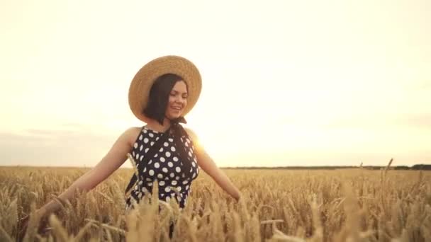 Vrolijke vrouw in stro hoed loopt in tarwe gouden veld tijdens zonsondergang. Meisje met plezier, glimlachend. Vrijheid, vreugde, geluk concept. — Stockvideo
