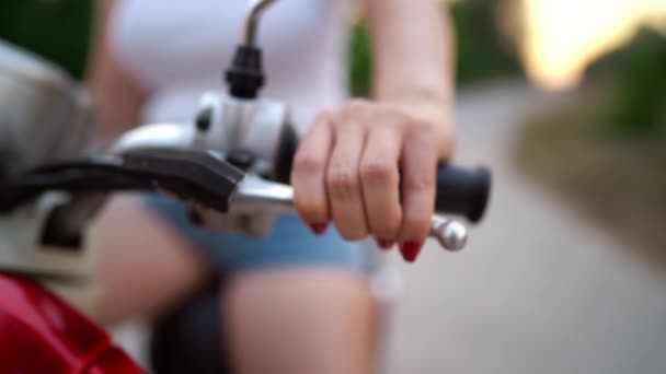 La mano femenina presiona el freno en el scooter retro vintage rojo. Vista de primer plano . — Vídeos de Stock