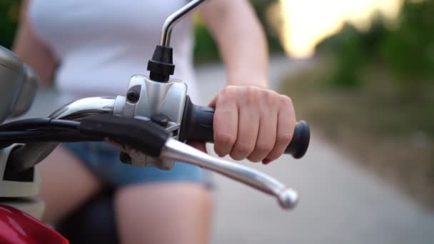 Manos femeninas conduciendo scooter retro rojo. Chica cabalga a lo largo del camino rocoso país. manos en el volante — Vídeos de Stock