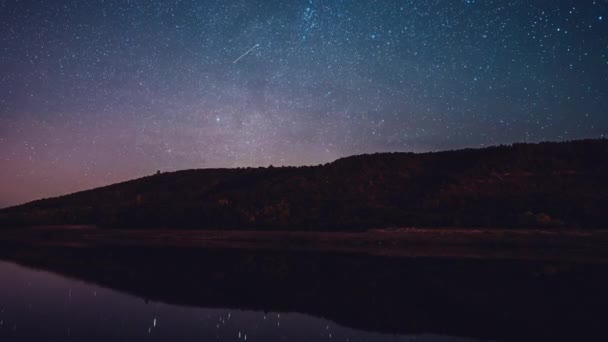 Starry sky over mountain and river at night.Constellations and planets beautifully reflected in water.Milky way passing in long exposure timelapse.Nature, universe, galaxy, astronomy concept. — Stock Video