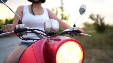 Mopedli kadın. Kırmızı vintage motosiklet veya scooter far lambası. Dolly atış.