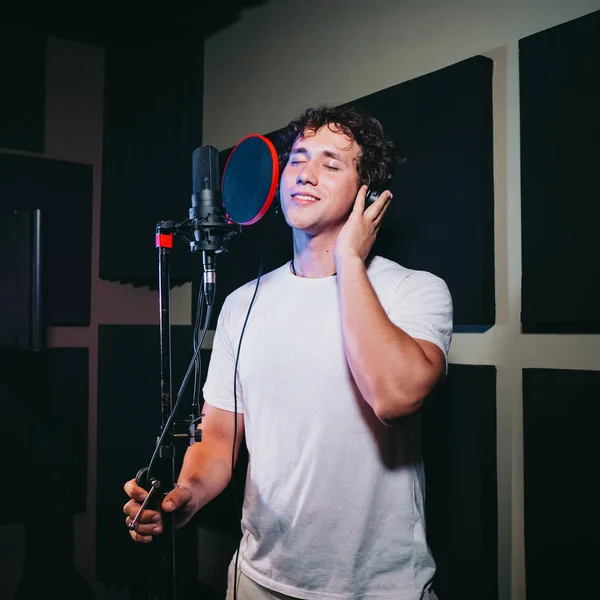 Un homme expressif chante une chanson dans un microphone dans un studio d'enregistrement . — Photo