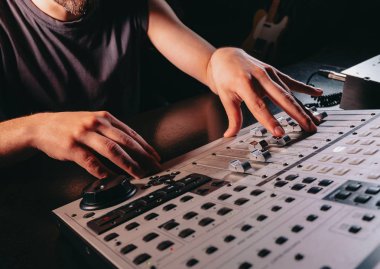 Tanınmayan ses üreticisi veya mühendisi, profesyonel kayıt stüdyosunda karıştırma konsolundaki kaydırma tekerleğidöndürür. Müzisyen yeni bir şarkı üzerinde çalışıyor. Eller kapanır.
