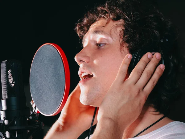 Artista vocal masculino com cabelo encaracolado cantando sozinho. Jovem cantor bonito homem emocionalmente escrever música no estúdio. Gravação de nova melodia ou álbum . — Fotografia de Stock