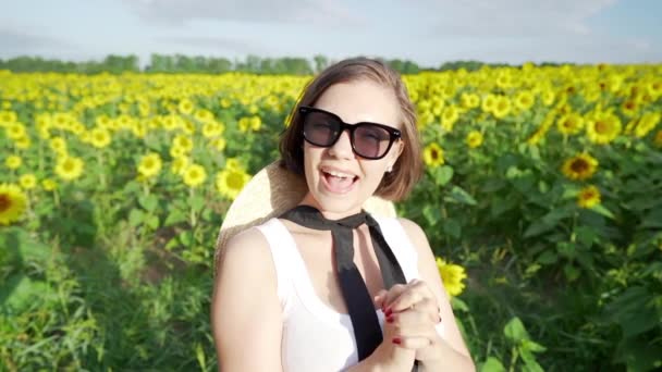 Jovem mulher bonita no campo de girassóis olhando para a câmera e sorrindo — Vídeo de Stock