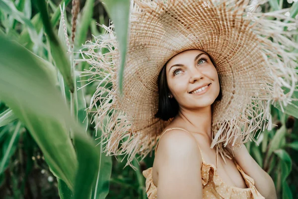 Портрет молодої красивої жінки у великому модному солом'яному капелюсі, що позує і посміхається в тропічних джунглях. Щастя, подорожі, концепція відпустки — стокове фото
