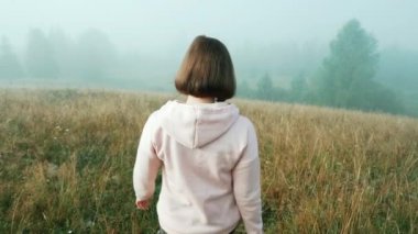 tanınmayan kadın dağdan sisin içine iner. Karpat dağlarında sabahın erken saatlerinde doğa. Seyahat konsepti.