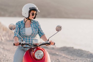 Çekici kız portresi. Renkli giysiler ve güneş gözlüğü lady gün batımı arka planda kırmızı retro moped üzerinde oturan. Seyahat konsepti.
