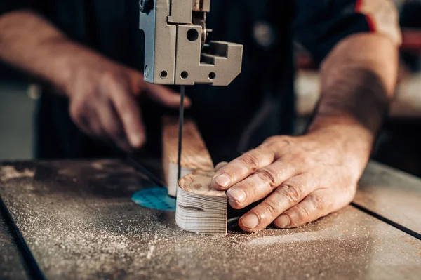 Carpintero trabajando en taller. El obrero carpintero corta tablón de madera en la máquina de rompecabezas. Trabajos manuales, concepto de carpintería, carpintería . — Foto de Stock