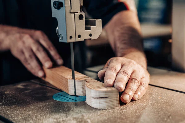 Carpintero trabajando en taller. El obrero carpintero corta tablón de madera en la máquina de rompecabezas. Trabajos manuales, concepto de carpintería, carpintería . — Foto de Stock