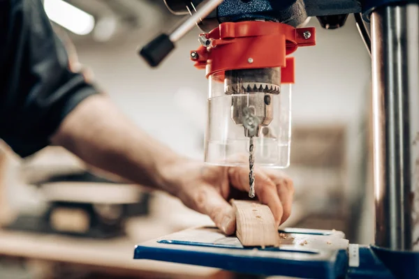 Carpintero hace agujero en la parte de madera con prensa de taladro. Joiner trabajando con las manos. Concepto de trabajo manual, taller de carpintería . — Foto de Stock
