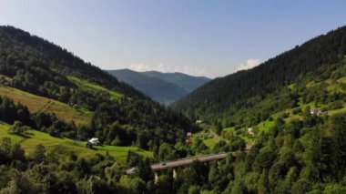 Aerial.Drone çarpıcı dağ doğası üzerinde ileri uçar. Avrupa'da Karpat dağları.Köydeki yükseklikten görünüm, gelişmiş altyapı, köprü, yol. 