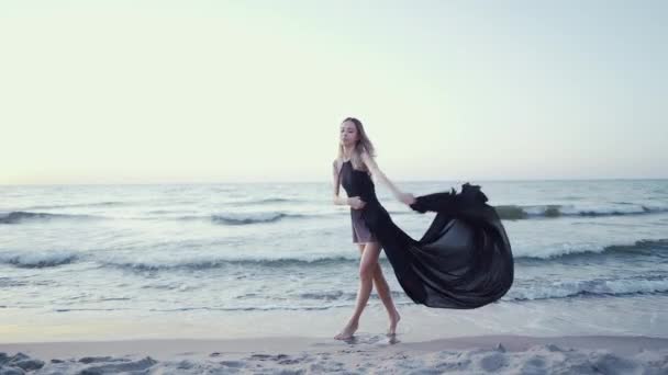 Fille dansante avec tissu noir sur fond de mer. Nature, ballet, concept de gymnastique. Femme danseuse qui s'étire. Une scène incroyable. Mouvement lent — Video