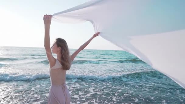 Närbild av ung kvinna som håller långa stora vita sidentyg som segel på havet eller havet stranden. Frihet, ömhet, resekoncept. — Stockvideo