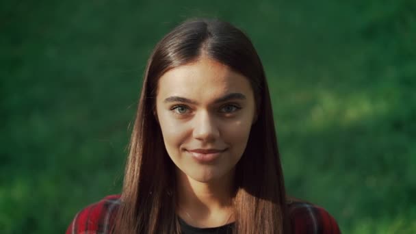 Porträt eines jungen attraktiven Mädchens im leeren Herbstpark.Frau blickt in die Kamera, lächelt.freundliches Aussehen moderner Hipster. — Stockvideo