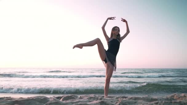 Kumlu kıyı şeridi üzerinde uzanan çekici balerin uygulamaları. Sanat kavramı, doğa güzelliği. Yavaş çekim. — Stok video