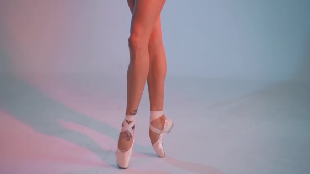 Nahaufnahme der Beine von Balletttänzern in Spitze. Frau übt Übungen auf buntem neonfarbenen Studiohintergrund. Ballerinas Füße in Schuhen. Mädchen zeigt klassischen Ballett-Pas. — Stockvideo