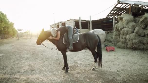 かわいい馬の女性は田舎の牧場で馬を抱きしめてキスします。愛、友情、家畜の概念。スローモーション. — ストック動画