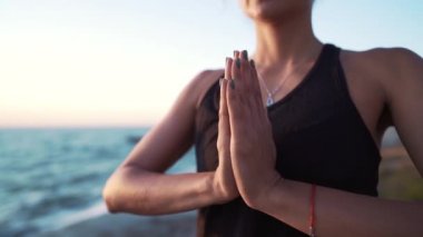 Siyah bodysuit genç kız deniz veya okyanus yakınında namaste mudra ile yoga pratik. Sağlıklı yaşam tarzı kavramı
