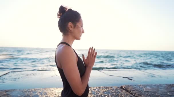 Mujer con rostro oriental practicando yoga, namaste gratitud mudra sola en la playa del mar.Chica concentrada durante el amanecer. Religión, pureza, resignación, concepto de espiritualidad . — Vídeo de stock