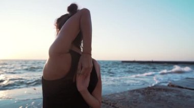 Siyah kostümk lüzrli genç kadın gün doğumu ışık, minimalist sahne yoga. Asana yapıyorum. Sağlıklı yaşam tarzı kavramı.