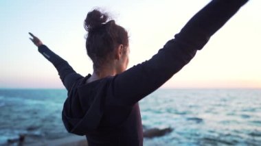 Hoş kadın deniz kıyısında gün doğumunda güneşe selam yapar. Yoga, meditasyon, sağlıklı yaşam tarzı kavramı.